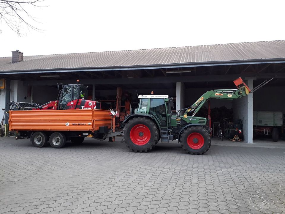 Fendt-Schlepper mit Frontlader, Kipper und Hoflader vor der Maschinenhalle