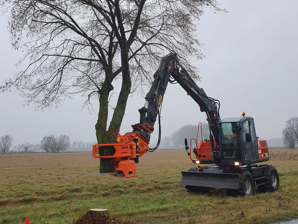 Mobilbagger Atlas 140W mit Fällgreifer Woodcracker an einem Baum am Feldrand