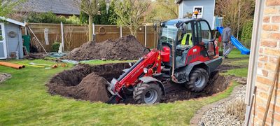 Schäffer-Hoflader transportiert Aushub für einen Pool im Garten