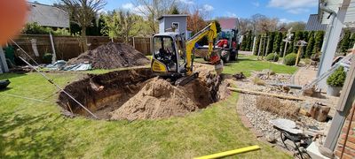 Minibagger hebt im Garten die Grube für einen Pool aus
