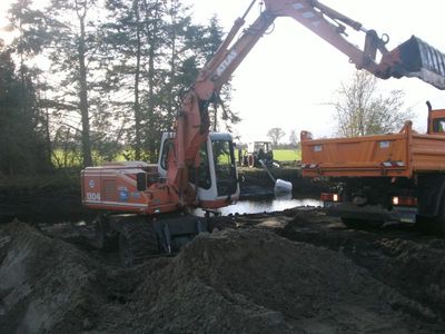 Bagger lädt Teichaushub auf einen Kipper