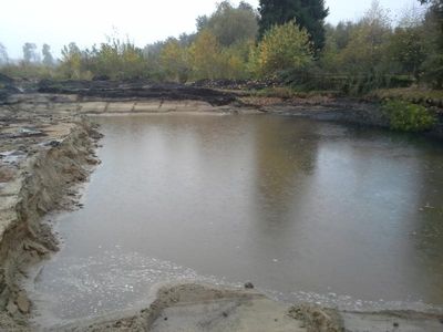 Frisch ausgehobener Teich mit Wasser